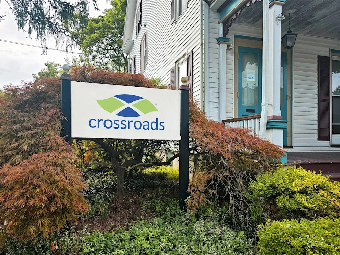 Crossroads Treatment Center sign in front of white house with blue door and autumn foliage