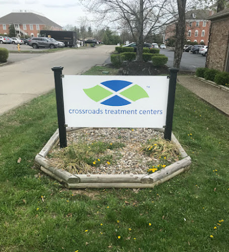 Crossroads Treatment Centers outdoor sign in landscaped bed with brick building and parking lot in background