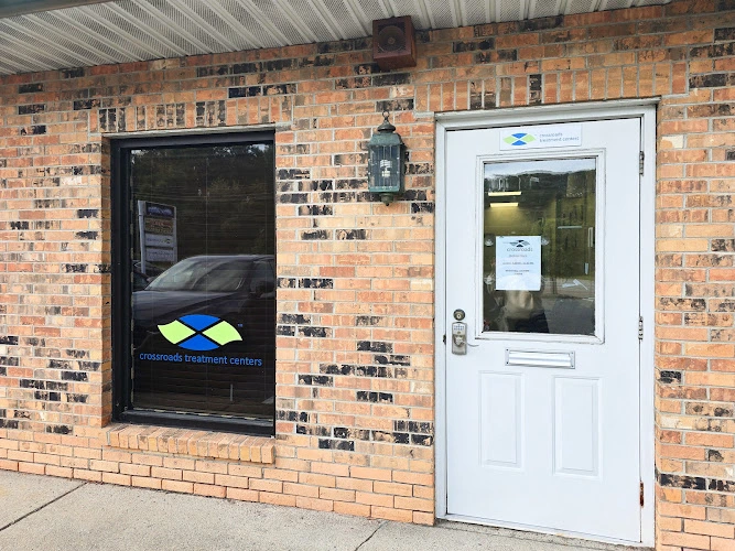 Brick building exterior with black door featuring Crossroads Treatment Centers logo and white entrance door