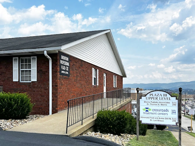 Brick medical building with white gable and ramp entrance, signage for Crossroads Treatment Center visible