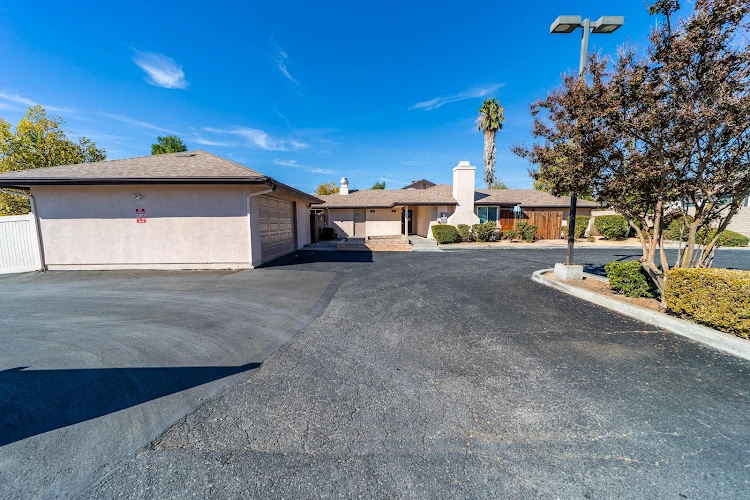 Single-story medical facility with driveway, palm trees, and clear blue sky