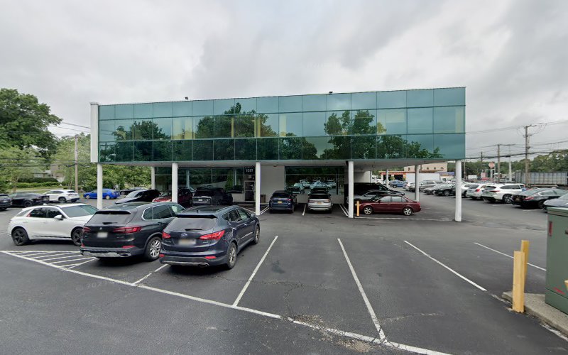 Modern glass-front medical building exterior with parked cars and clear sky
