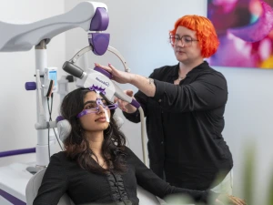 Clinician administering TMS therapy to patient wearing protective eyewear in medical office