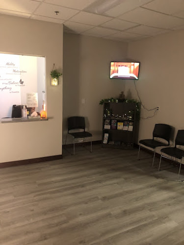 Reception desk and waiting area with chairs, plant, and wall-mounted display screen