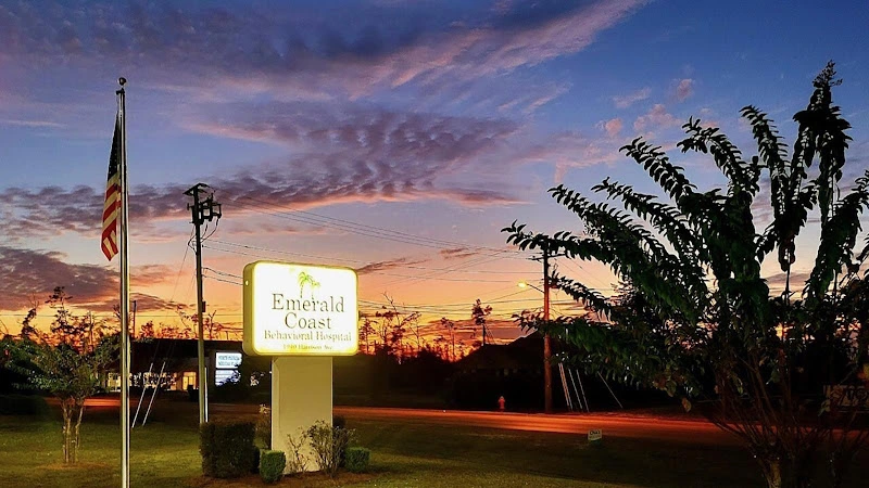 Emerald Coast Behavioral Hospital illuminated sign at dusk with American flag and landscaping