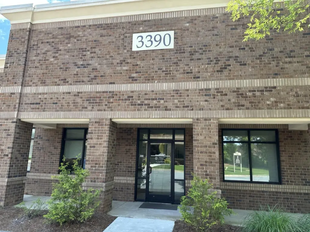 Brick building exterior at 3390 with glass entrance doors and landscaping