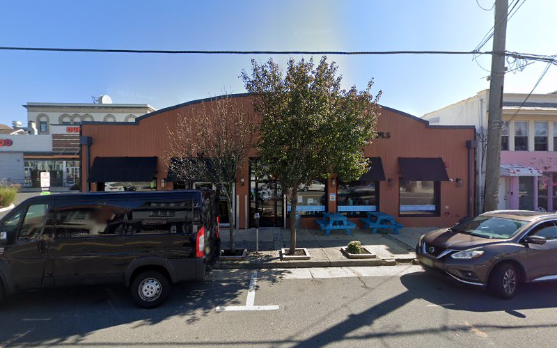 Brick storefront with blue awnings and parked vehicles on street