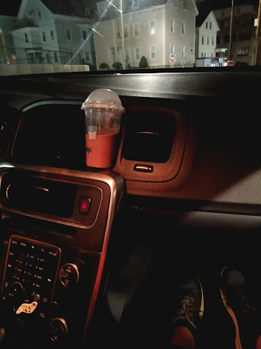 Red beverage cup on car dashboard at night with illuminated church buildings visible through windshield