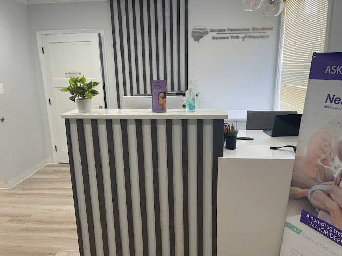 Reception desk with black and white striped panel, potted plant, computer monitor, and treatment information displays