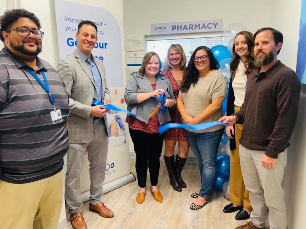 Seven staff members cutting blue ribbon at Genoa Pharmacy opening ceremony