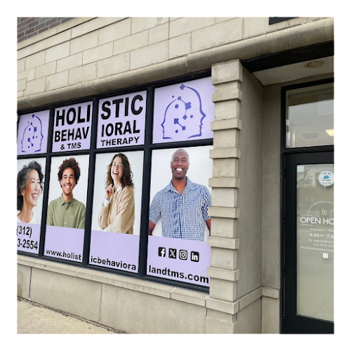 Storefront window display featuring Holistic Behavioral & TMS Therapy signage with photos of four diverse individuals and contact information
