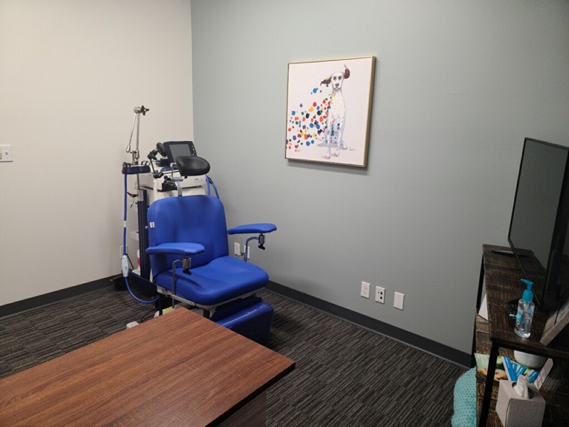 TMS therapy room with blue treatment chair and overhead magnetic stimulation equipment