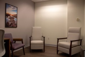 Quiet consultation room with three upholstered chairs and landscape photograph on wall