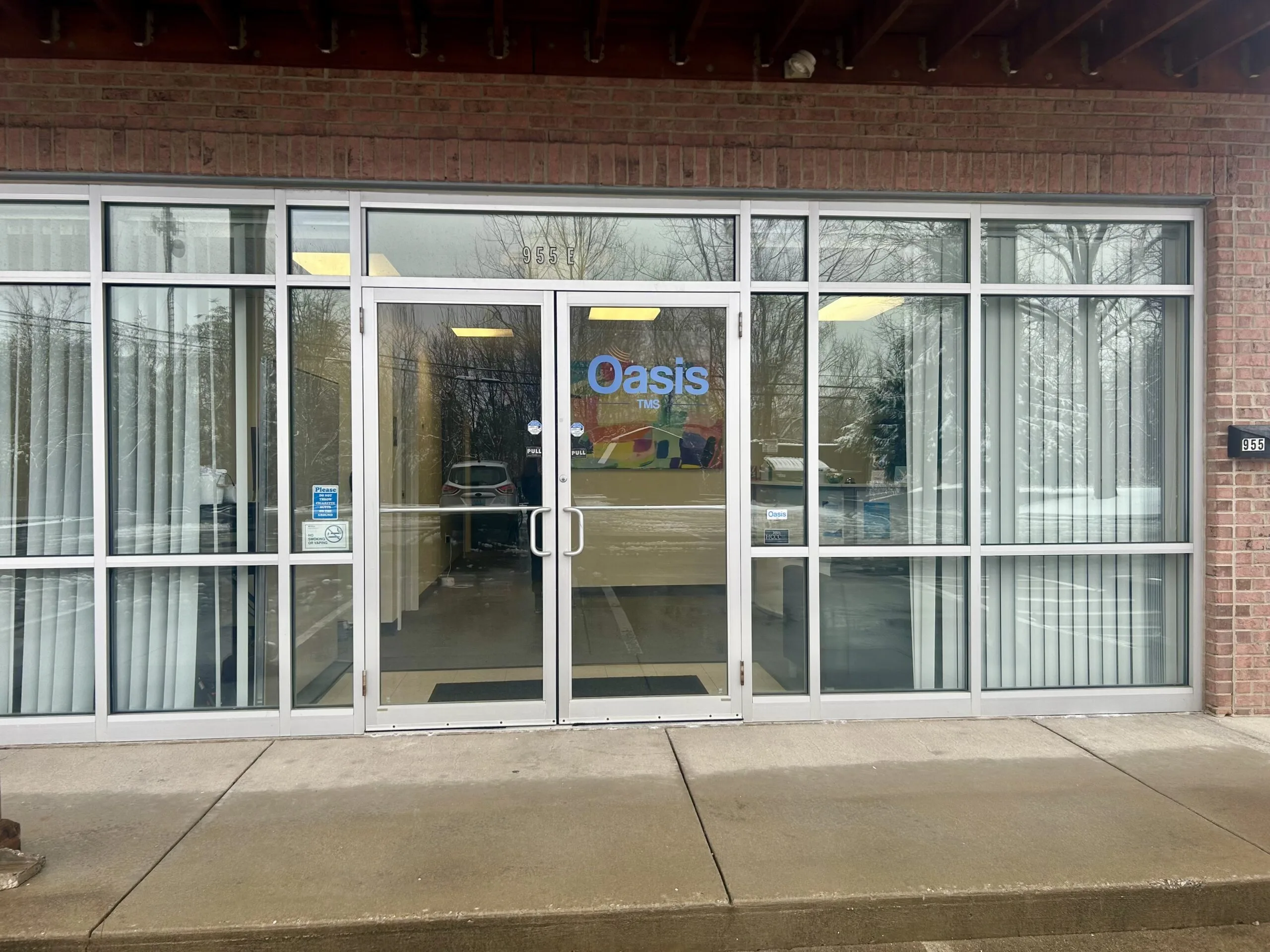 Oasis TMS clinic storefront entrance on brick building with glass doors and windows