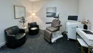 TMS treatment room with Apollo device, patient chair, black armchairs, and computer workstation along the wall