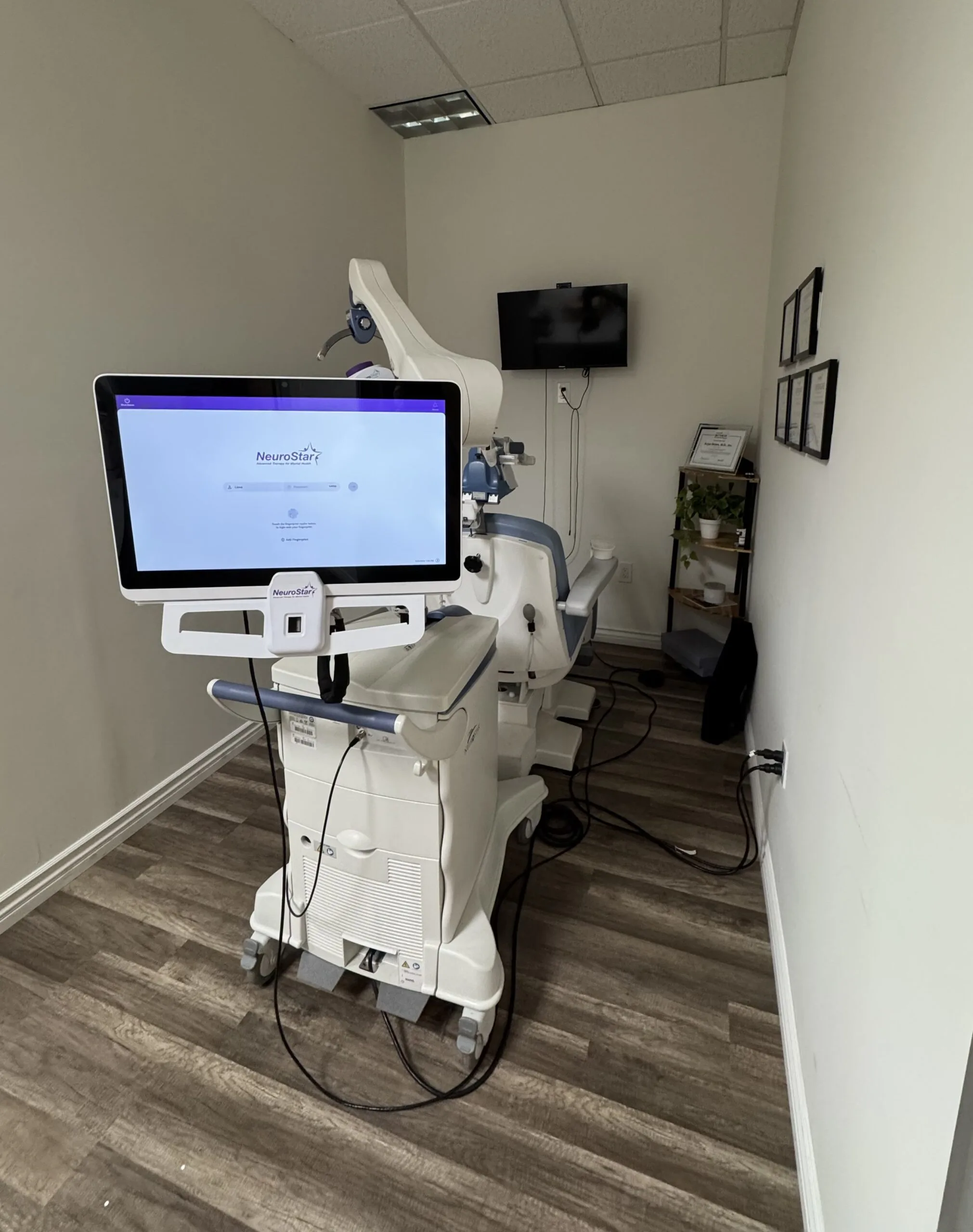 NeuroStar TMS device with monitor and coil in clinical treatment room