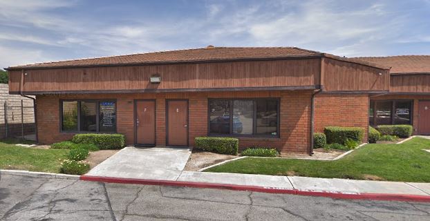 Brick medical building exterior with red doors, windows, and landscaping in Moreno Valley