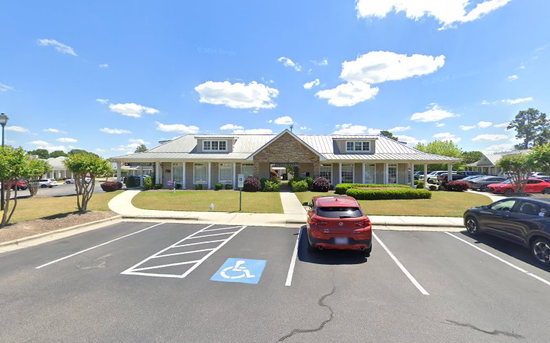 Psychiatry practice exterior with stone and white columned building, parking lot with handicap space, landscaping, and cars
