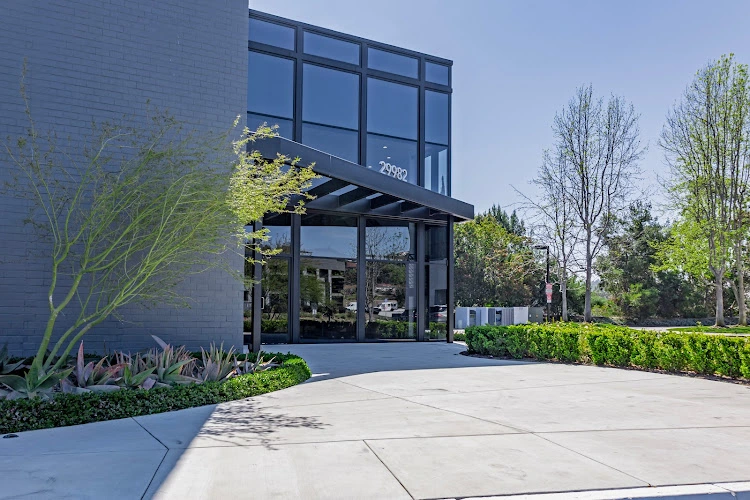 Modern medical building exterior with black-framed windows, brick facade, and landscaped courtyard