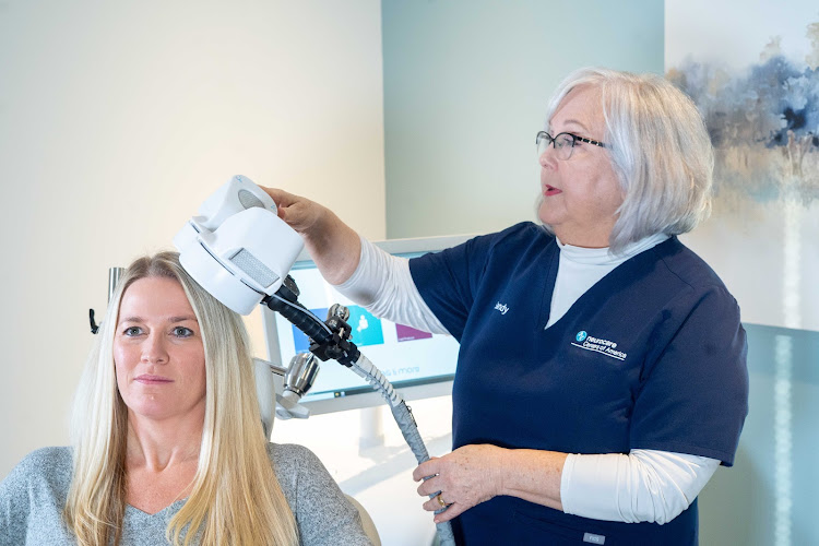 Clinician administering transcranial magnetic stimulation therapy to a seated patient