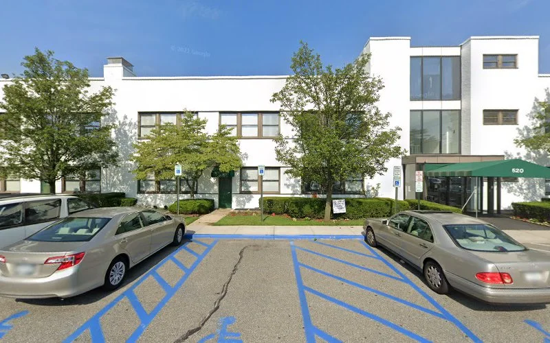 Modern white multi-story medical office building with accessible parking spaces and green landscaping
