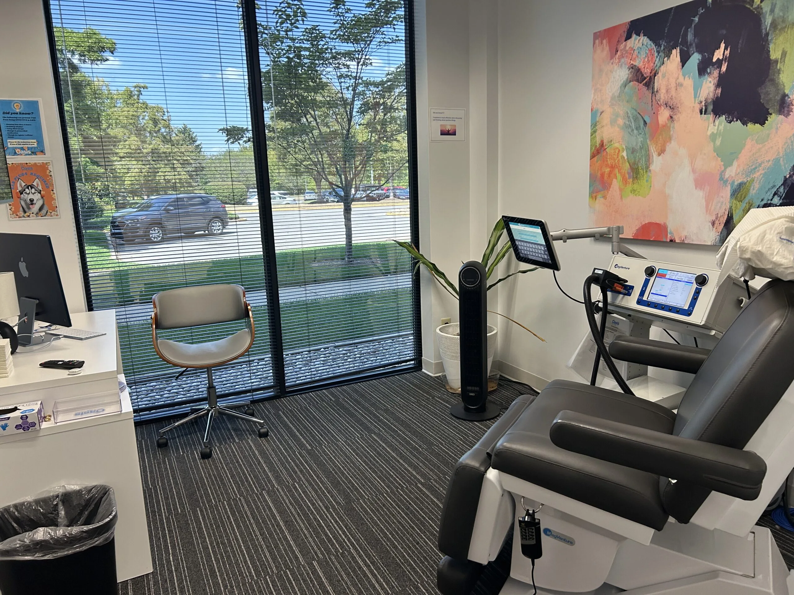 Louisville TMS clinic room with treatment chair, medical equipment, desk, and large windows