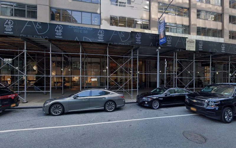 Manhattan street-level storefront with construction scaffolding and parked cars