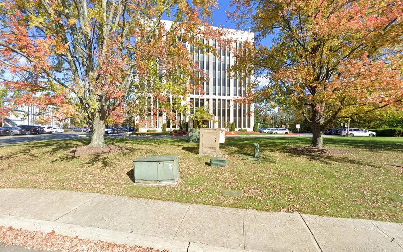 Medical office building with vertical striped white exterior among autumn trees and manicured lawn