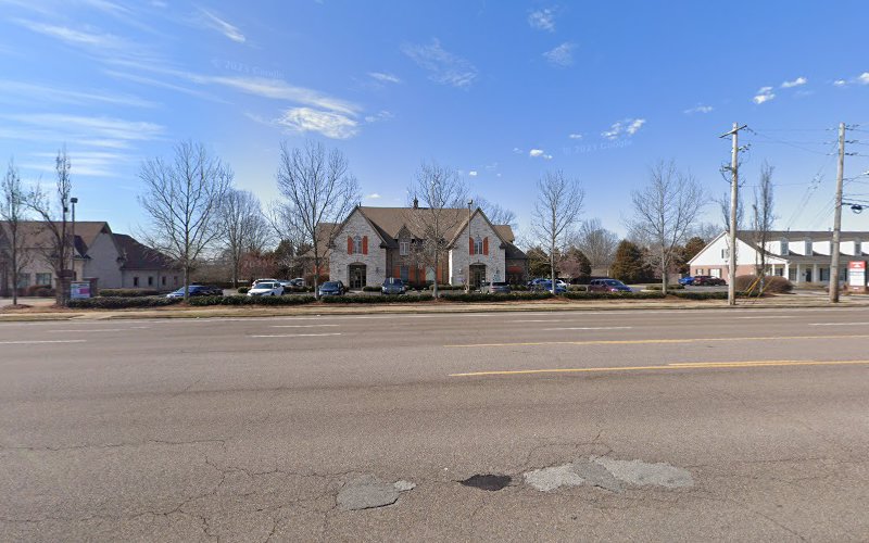 Brick medical building with stone accents on a Memphis street lined with bare trees and parked cars