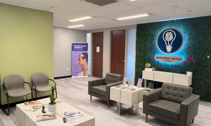 Modern Mind Clinic reception area with neon logo, green plant wall, and gray seating