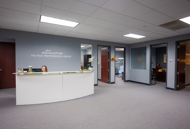 Reception area with curved white desk and staff member, Ascend TMS signage visible on wall