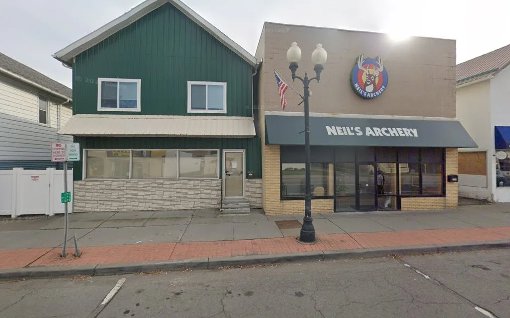 Neurosciences Group TMS therapy clinic storefront on street with Neil's Archery next door