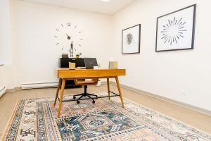 Northbrook clinic workspace with wooden desk, wall clock, laptop, and framed artwork