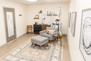TMS therapy treatment room with gray armchair, ottoman, desk, and treatment equipment in Northbrook clinic
