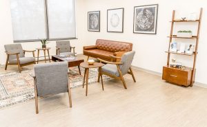 Northbrook clinic waiting area with cognac leather sofa, gray chairs, and wooden shelving unit