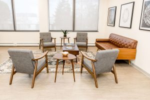 Seating area in Northbrook clinic with four gray chairs arranged around coffee tables and cognac sofa