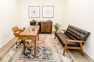 Northbrook clinic office with wooden desk, orange chair, black leather sofa, and storage cabinets