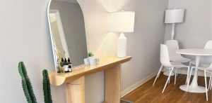 Clinic consultation room with wooden vanity, arched mirror, lamp, and dining table setup
