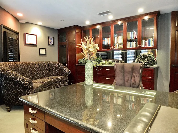Modern TMS therapy office waiting area with patterned sofa, granite countertop, dark wood cabinetry with glass doors, and white flower arrangement