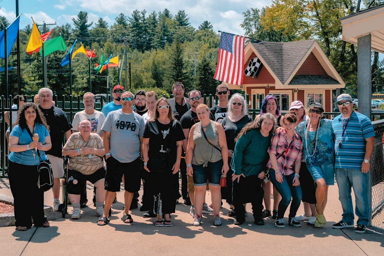 Group of people standing outside in front of a building with colorful flags and American flag