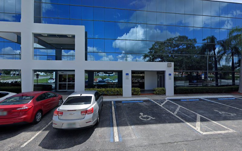 Modern white building exterior with blue glass panels, parked cars, and accessible parking spaces