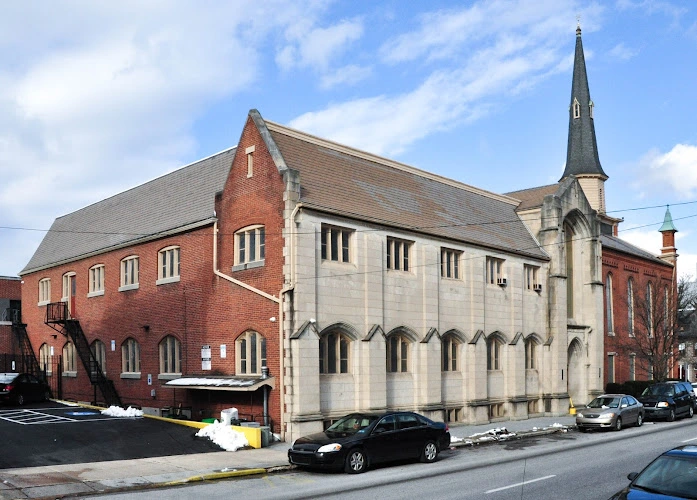 Red brick and white stone church buildings on street corner with parked cars