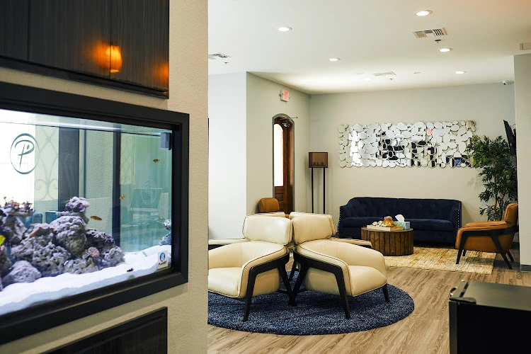 Prime Psychiatry & TMS Center waiting room with aquarium, cream seating, dark sofa, and decorative wall art
