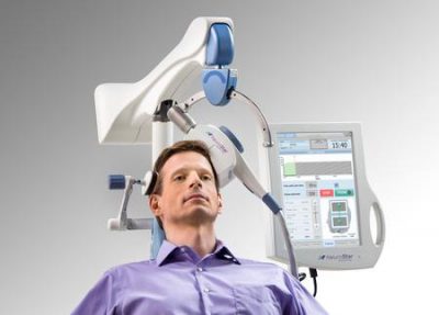 Patient receiving transcranial magnetic stimulation with TMS device positioned above head