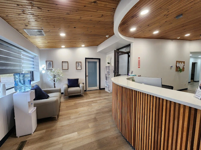 Promont Wellness modern reception area with wood-slat desk, contemporary furniture, and warm wood ceiling