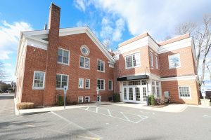 Red brick medical office building with white trim and entrance awning, daytime