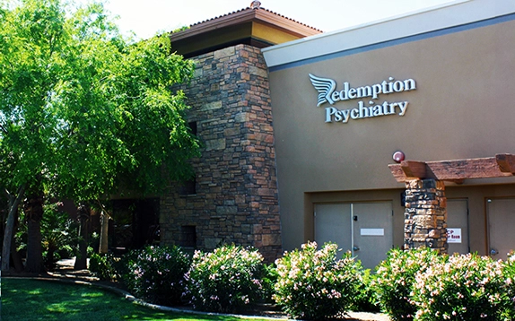Redemption Psychiatry building exterior with stone chimney, tan walls, and landscaping