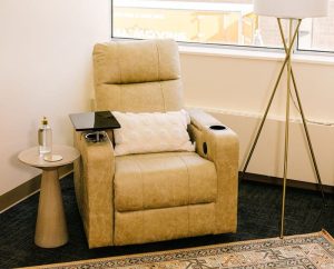Reclined gold leather treatment chair with white pillow and side table holding personal items