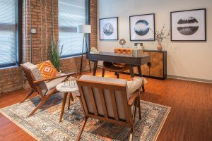 Modern therapy office with mid-century furniture, exposed brick, desk, and three circular landscape artworks on cream wall