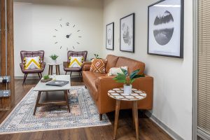 Consultation room with leather seating, side tables with plants, wall clock, and framed artwork
